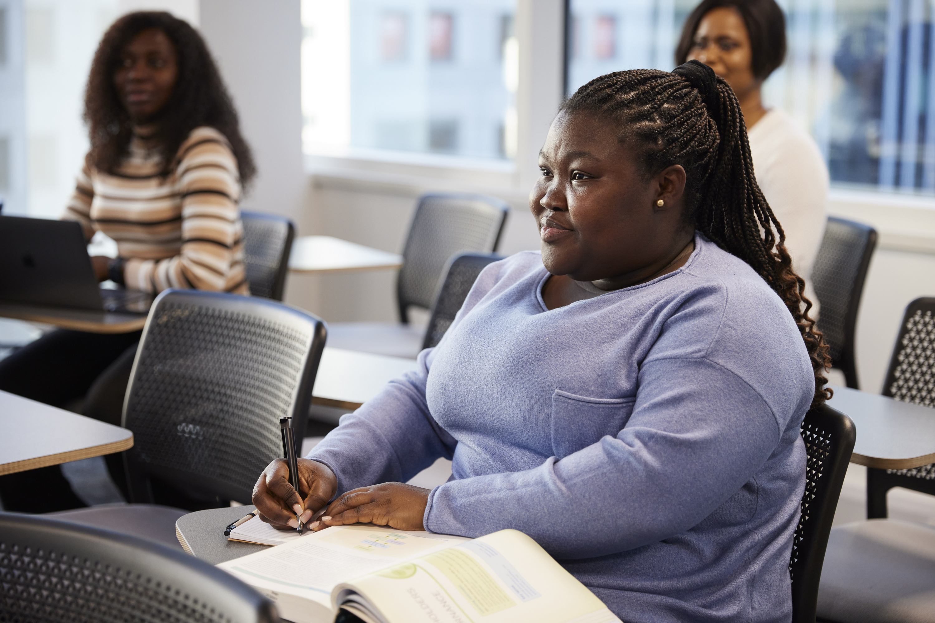 A student taking notes and listening during a lecture in a classroom